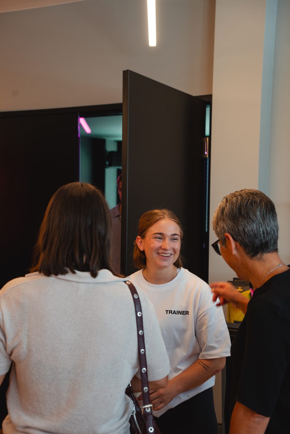 Sarah begrüsst zwei Mitglieder am Eingang von PowerHouse in Schaan